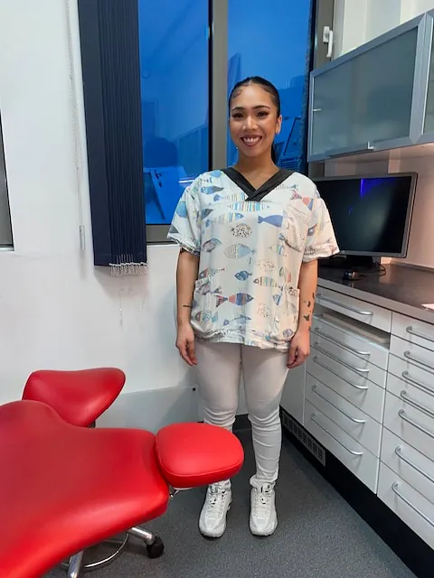 Smilende tannlege står på tannlegekontor