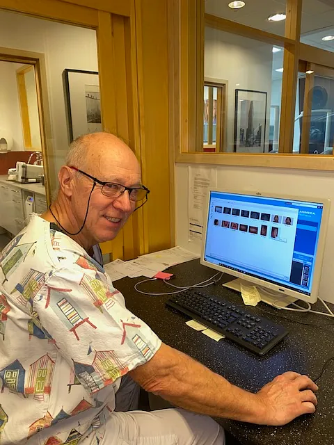 Per smiler til kamera mens han jobber med pc på kontor